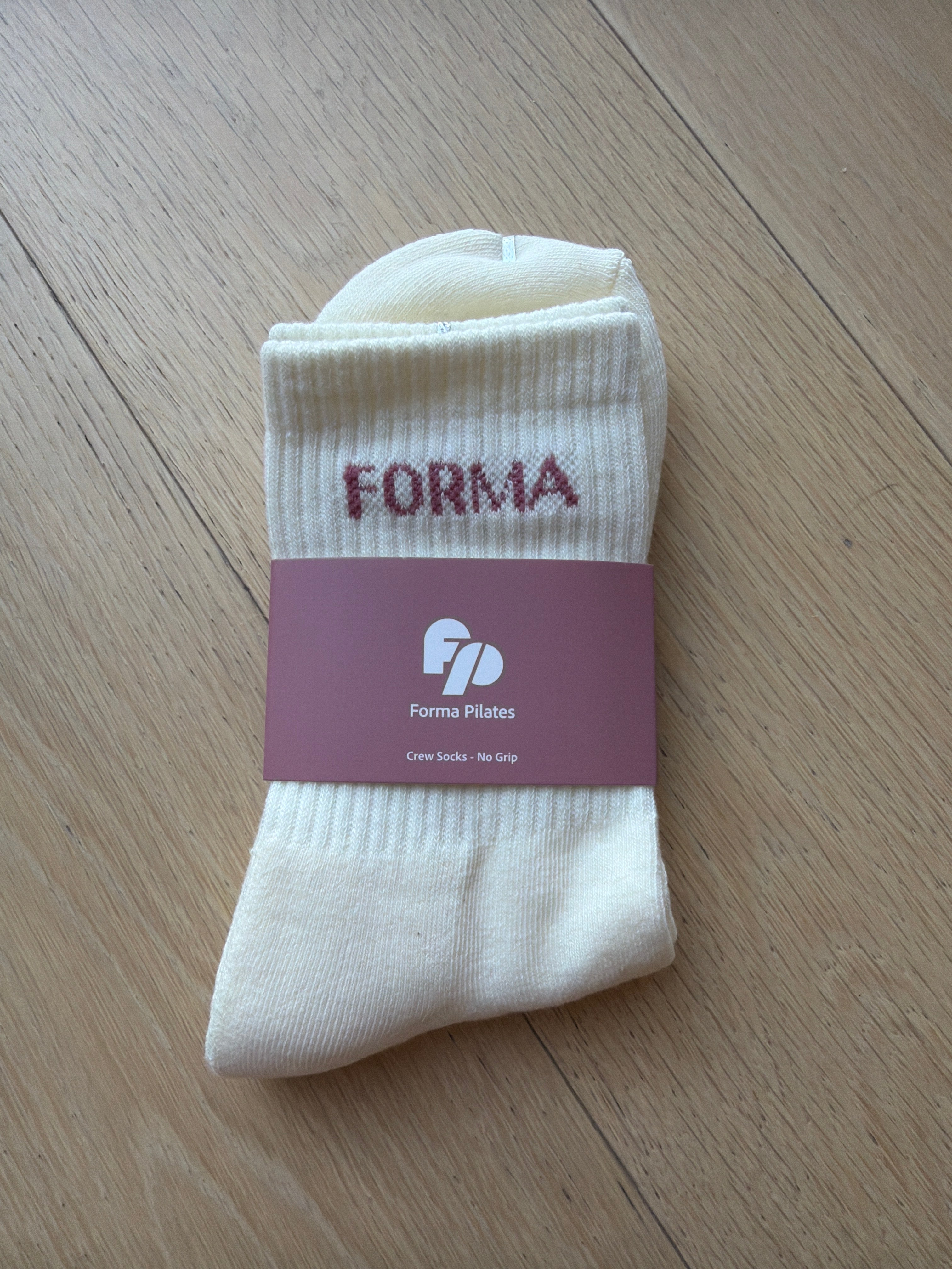 White sock with a purple 'FORMA' label on a wooden surface